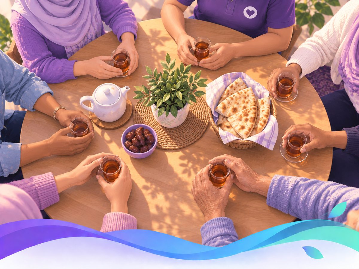 Many hands around one round table, sharing tea, bread and a plant